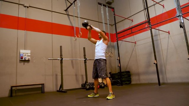 Muscular man exercising with a kettle bell at the Gym in Slow Motion.