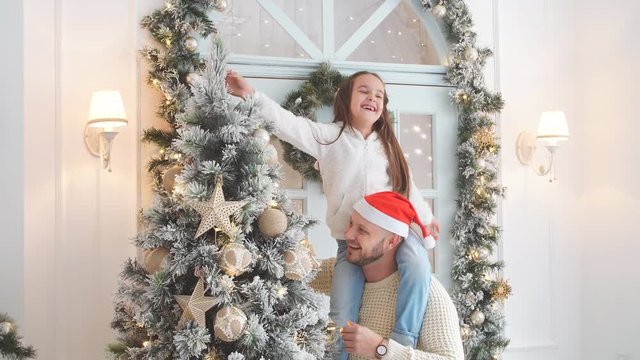 Cute girl and father decorating firtree on Christmas eve