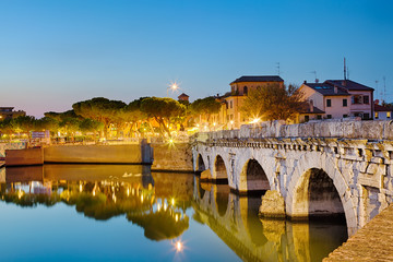 Fototapeta premium Historical roman Tiberius bridge over Marecchia river during sunset in Rimini, Italy.