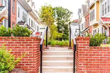 Fototapeta na wymiar Row of colorful, red, yellow, blue, white, green painted residential townhouses, homes, houses with brick patio garden stair entrance in summer