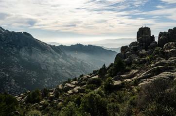 Some climbers at the very top of a rounded rock in La Pedriza Regional Park, Madrid