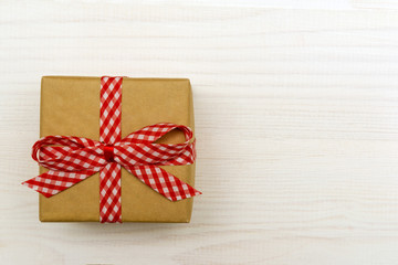 Present in gift box package on white wooden table. Copy space.