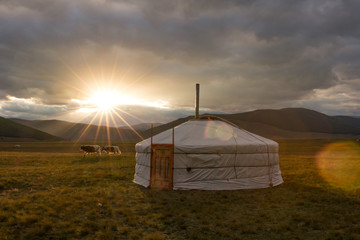 Traditional Mongolian yurt in the glare of a setting sun.