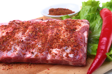 Raw pork ribs with herbs and spices on wooden board. Ready for cooking.