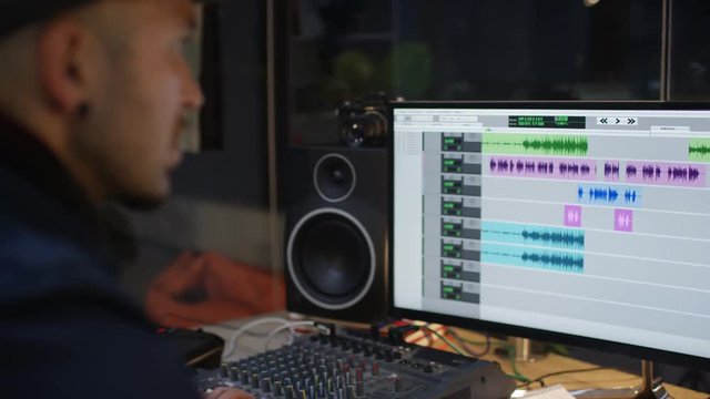  Musician in home recording studio arranging sound at the mixing desk