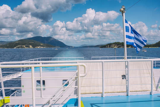 The Greek flag on the ship against the background of the sea of islands and opposite the ships. Sea voyage in the Ionian sea.
