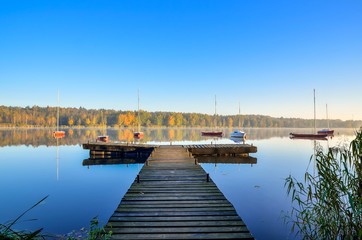Fototapeta na wymiar Beautiful autumn landscape. Wooden pier and boat on the lake.