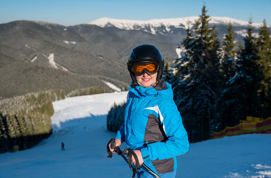 Shot of a female skier smiling to the camera joyfully while skiing on the snowy slope in the mountains at the ski resort on a sunny winter day beautiful landscape on the background copyspace