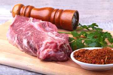 Raw beef steak with spices Leaves of coriander on wooden cutting board. Ready for cooking.