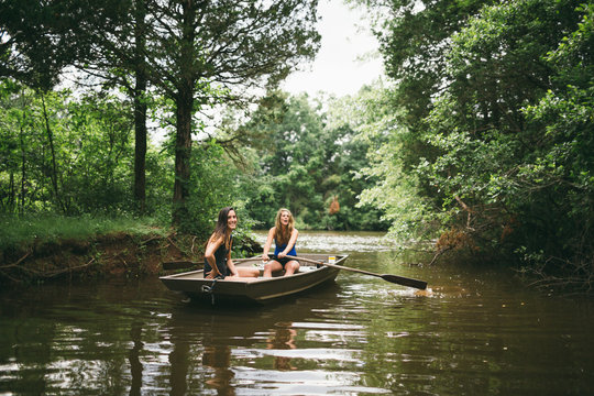 Two young girls explore a beautiful lake by rowboat