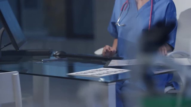  Nurse in modern hospital studying patient x rays & working on computer