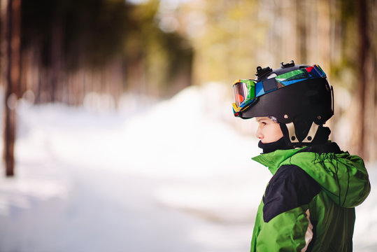 Young boy stands outside with ski helmet and goggles, ready to set of for a day skiing
