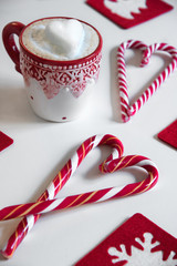 Cup of coffee with heart shape and christmas candy on the white background.