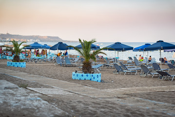 Sand beach decorated with palm trees in Faliraki town on Rhodes island, Greece