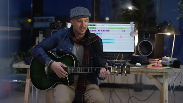  Musician playing guitar & singing in home recording studio