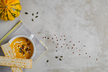 Bowl of pumpkin cream soup on light minimal background. Top view with copy space.