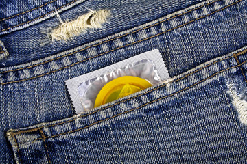 Yellow condom in the pocket of a blue jeans