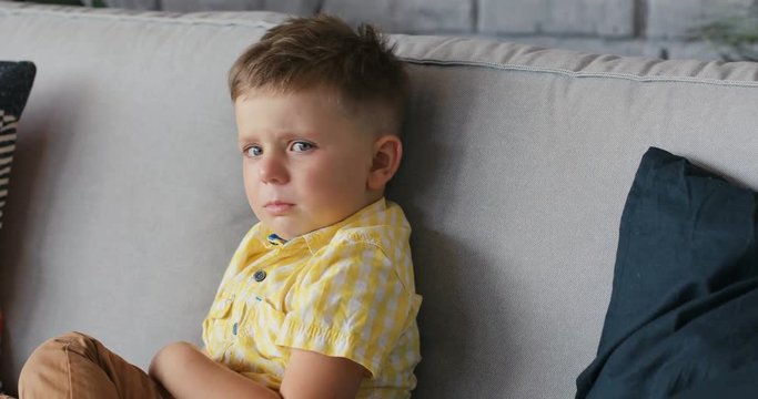 Portrait of a young boy cry sad at home sit on sofa unhappy alone depressed angry disappointed screaming child face frustration kid childhood Slow Motion Shot. Shot on RED EPIC camera