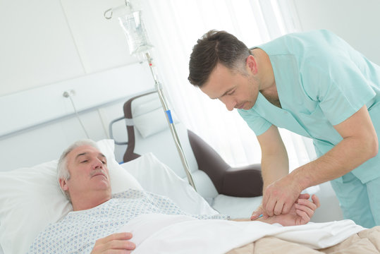 mal nurse visiting senior patient in hospital