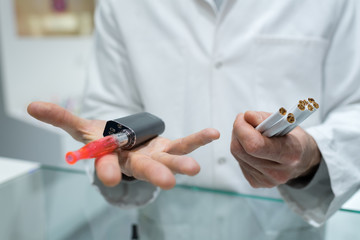 hands holding classic cigarettes and electronic cigarette