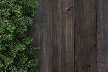 Christmas fir tree branches on dark rustic wooden background with copy space for text