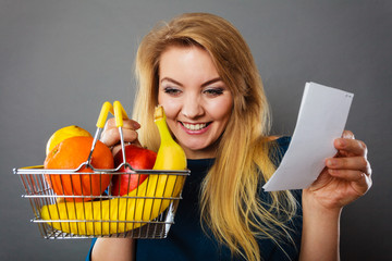 Happy woman holding shopping basket with fruits