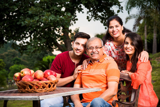 group photo of happy indian family sitting over lawn chair

