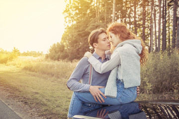 Travel. Couple hugging and kissing on the car's hood