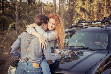 Travel. Couple hugging and kissing on the car's hood