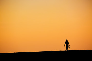Fototapeta na wymiar Silhouette man with big telephoto lens against orange sunset sky background.