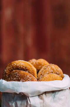 apple cider doughnuts in a bag against a red barn wall