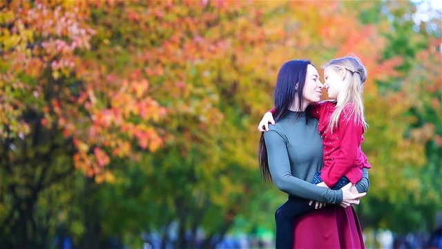 Family of mother and kid outdoors in park at autumn day