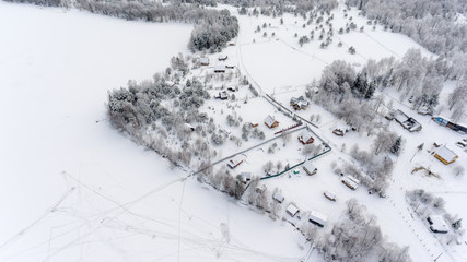 Aerial view at Russian winter village on the frozen lake shore. Timber houses and farms. Russia