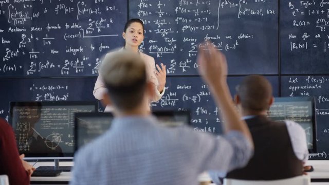  Teacher in adult education class explaining math formulas to students