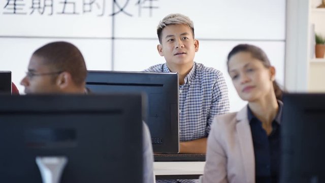  Adult students in language class with video screen showing Asian characters