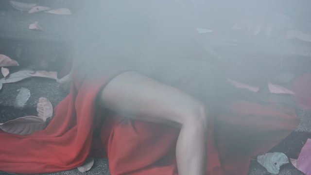 Mysterious woman in red dress with gunshot wound in her head sitting on the concrete stairs -  slow motion concept