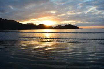 Naklejka na ściany i meble Sunrise on the beach in Ubatuba, with reflection in the sea