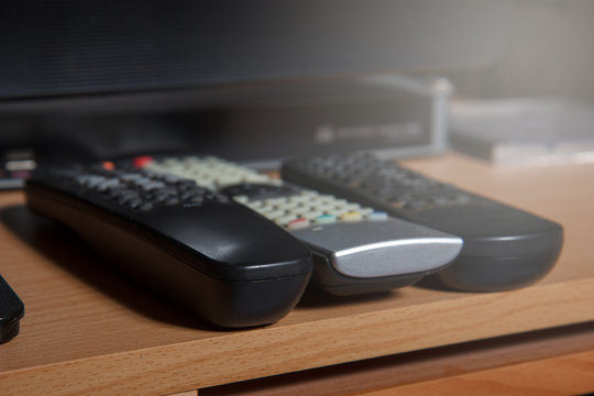 three remote controls on table below tv and media box
