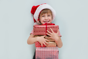 Happy child in Santa red hat holding Christmas present. Christmas time..