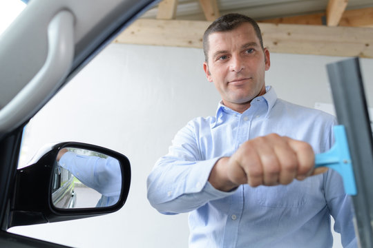 man cleaning car window with squeegee