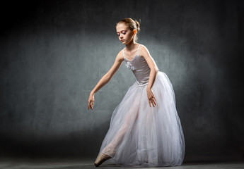 Fototapeta premium A young beautiful ballerina is posing in the studio. A little dancer. Ballet.