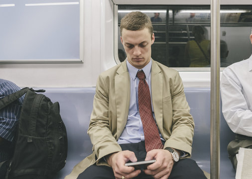 Male Student-Intern Using Smartphone in Train of Subway Transportation of New York