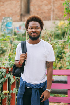 Portrait of beautiful afro man standing in front urban garden.