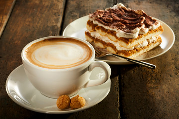 Cup of milk coffee with piece of cake - obrazy, fototapety, plakaty
