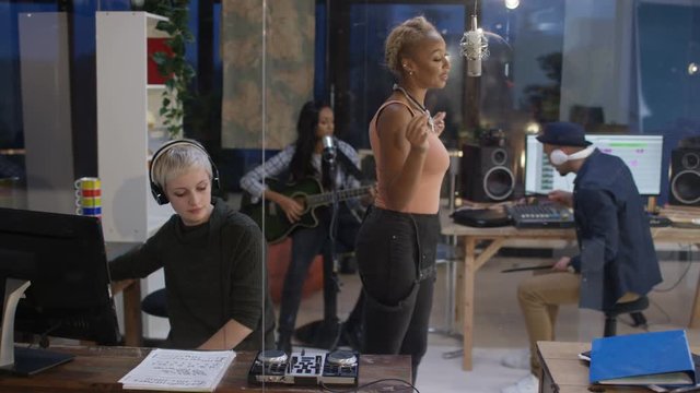  Musicians in recording studio recording a track with female vocalist