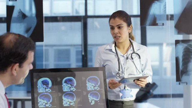  Medical team in a meeting, using technology to look at brain scans & x-rays.