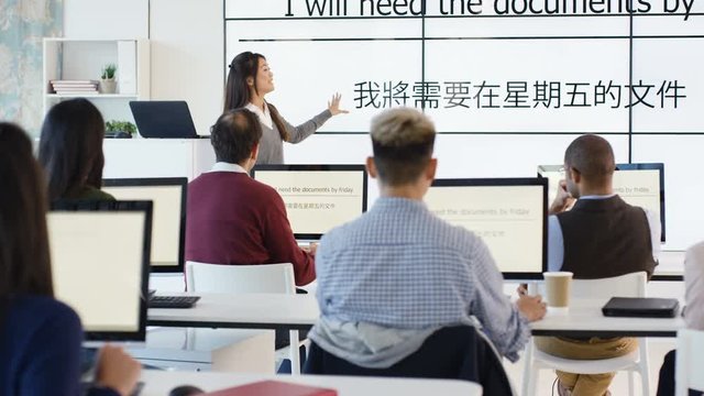  Adult students in language class with video screen showing Asian characters