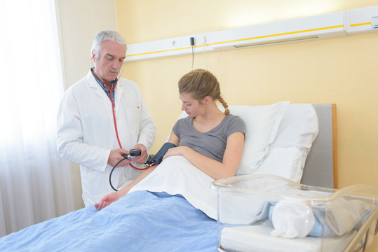 male doctor checking pregnant woman blood pressure in hospital