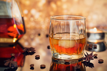 Cognac or liqueur, coffee beans and spices on a glass table.