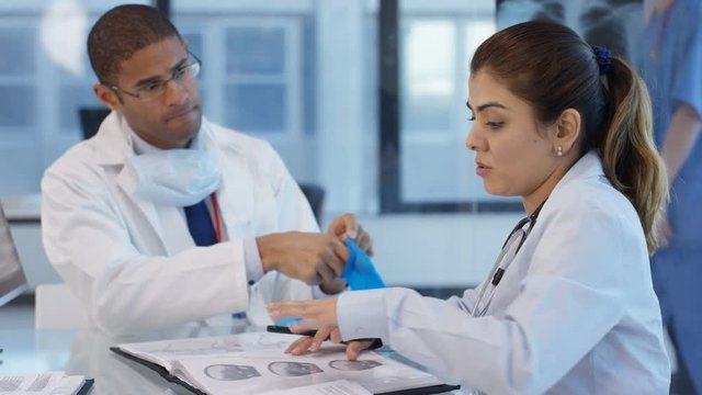  Hospital doctor in a meeting with colleague, putting on gloves before an exam